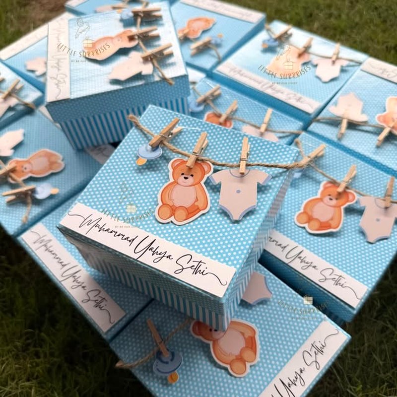 Blue polka-dot announcement boxes with teddy cut-outs pegged on twine